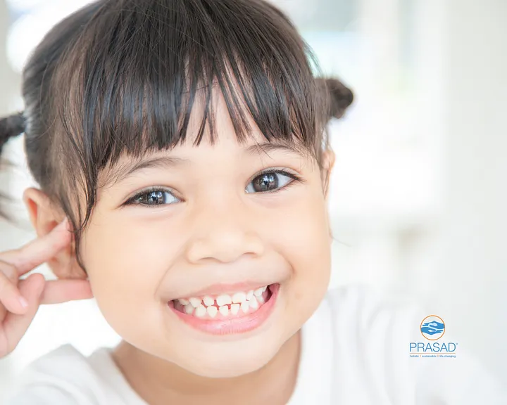 Smiling young child with healthy teeth, featured in PRASAD’s article on preventing tooth decay in children.